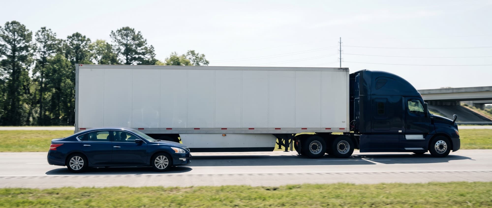 A car driving alongside a semi-truck on a Louisiana interstate